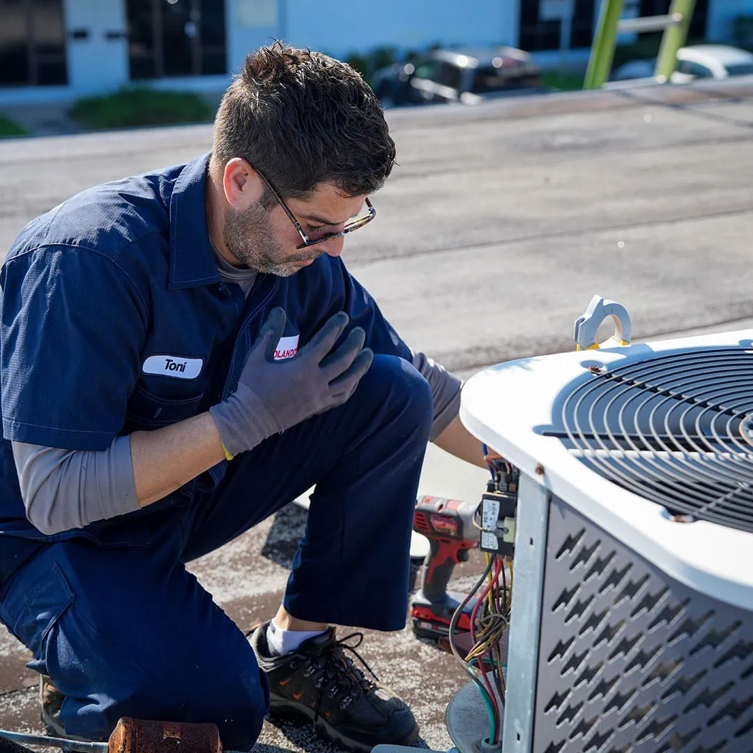 Rolando's HVAC technician servicing an outdoor air-conditioning unit